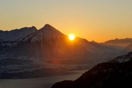 a sunset over a mountain with a body of water at Otium-Oberhofen in Oberhofen am Thunersee