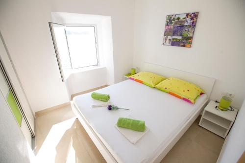 a small bedroom with a white bed and a window at Apartmani Cindrić in Karlobag