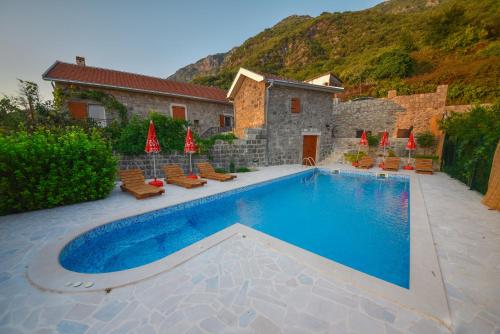 a swimming pool with chairs and a house at Mediteraneo Villa in Kaluđerovići