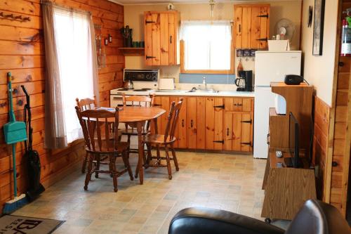Blue Crest Cottages في نورث روستيكو: مطبخ مع خزائن خشبية وطاولة وكراسي