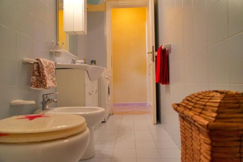 La salle de bains est pourvue de toilettes blanches et d'un lavabo. dans l'établissement residence ulisse, à Santa Teresa Gallura