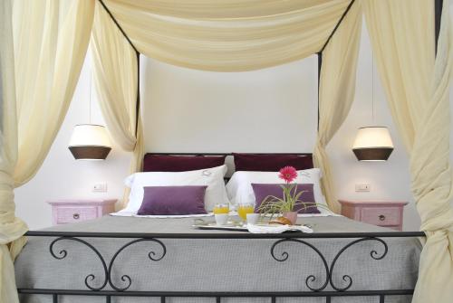 a bedroom with a canopy bed with a table with drinks at Masseria Panareo in Otranto