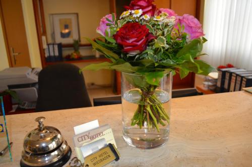 a vase of flowers sitting on top of a table at City Hotel Wiesbaden in Wiesbaden