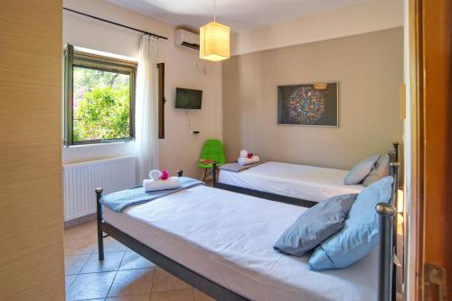 a bedroom with two beds and a window at Villa Kiki Paxos Ozias in Gaios