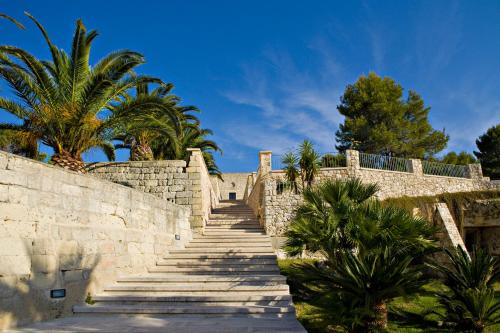 a stairway with palm trees and a stone wall at Masseria Panareo in Otranto