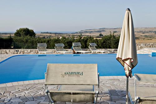 a chair and an umbrella next to a swimming pool at Masseria Panareo in Otranto