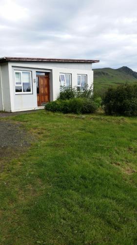 una pequeña casa blanca con un patio de césped en Giljur Guesthouse, en Vík
