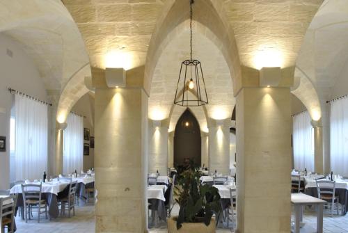 a dining room with white tables and a chandelier at Masseria Panareo in Otranto