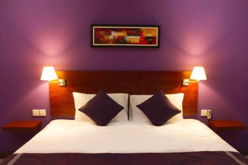 Un dormitorio con una cama blanca con paredes moradas en Melasa House, en Senggigi 