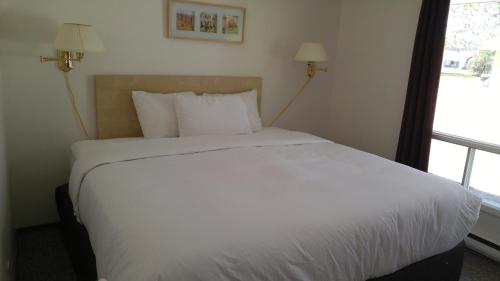 a bed with a white comforter and pillows at Tulip Inn in Huntsville