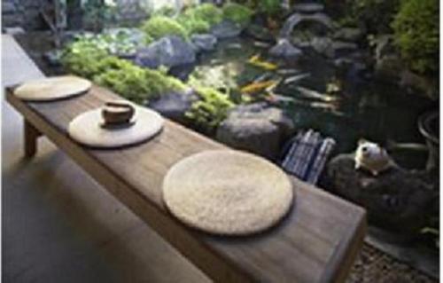 a wooden table with two hats on it next to a fish pond at Gingetsu in Shimo-suwa
