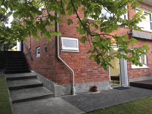 a brick building with stairs leading up to a window at Whitby Studio - Mairangi Bay Beach in Auckland