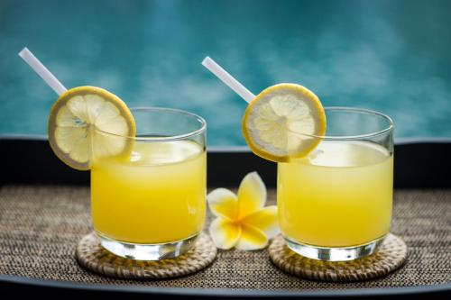 two glasses of orange juice and lemon slices on a table at Kubu GWK Villa in Jimbaran