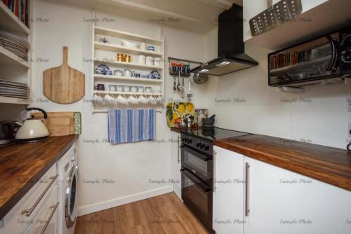 メードストンにあるThe Butteryの白い壁と木製のカウンターが備わる小さなキッチン