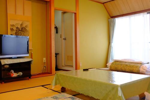 a living room with a table and a tv at Mizuhokan in Ise