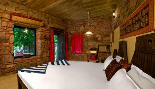 a bedroom with a large bed in a stone wall at The Mandore - a leafy resort in Jodhpur