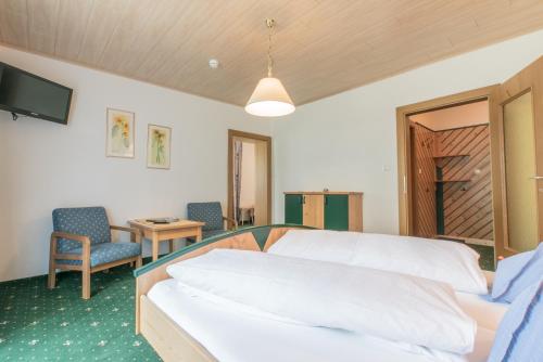 a bedroom with a bed and a chair and a television at Pension Trojerhof in Heiligenblut