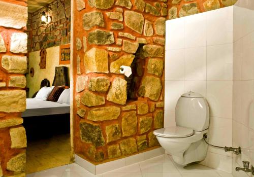 a bathroom with a stone wall with a toilet in it at Mandore Guest House in Jodhpur
