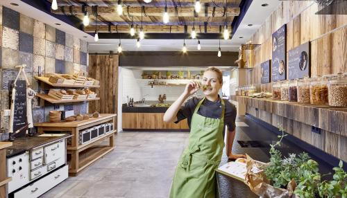a woman in a green apron eating food in a bakery at Hotel Penzinghof in Oberndorf in Tirol