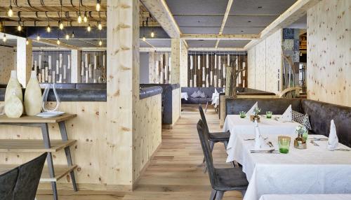 a restaurant with white tables and chairs and wooden walls at Hotel Penzinghof in Oberndorf in Tirol