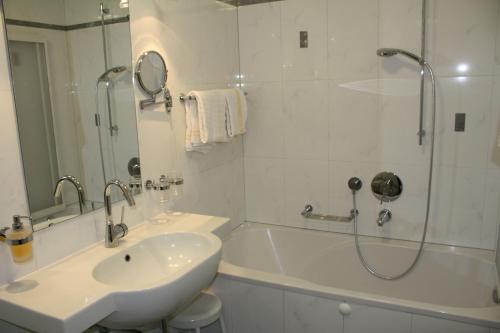 a white bathroom with a sink and a shower at Hotel Zebru in Solda