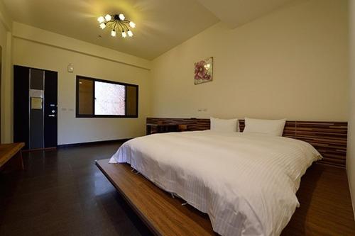 um quarto com uma grande cama branca e uma janela em Shan Jhong You You B&B em Lugu