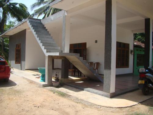 a house with a staircase on the side of it at Priyanna Guest, Forest view in Polonnaruwa