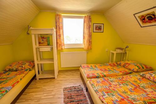 two beds in a room with yellow walls and a window at Domceky Holiday in Liptovský Trnovec