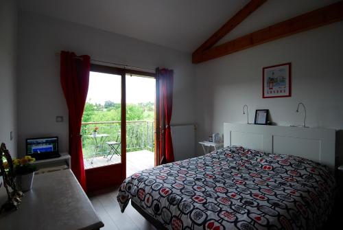 a bedroom with a bed and a sliding glass door at Maison d'Hôtes des 2 Chênes in Bessenay