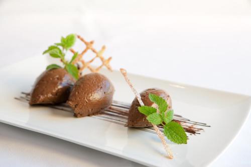three chocolate desserts on a white plate with mint at Hotel Walliserstube in Damuls
