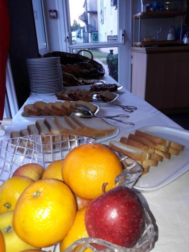 Un buffet de comida con manzanas y naranjas en una mesa. en Hôtel Le Cosy Blois Villebarou, en Blois