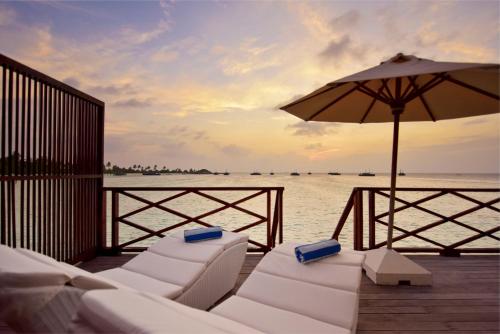 a group of white chairs and an umbrella on a dock at Safari Island in Mushimasgali