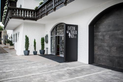 a white building with a black door and potted plants at Garni Hotel Katzenthalerhof in Lana