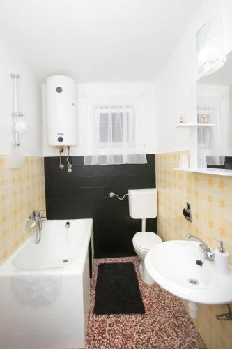 a bathroom with a sink and a toilet and a tub at Old SALONA in Solin