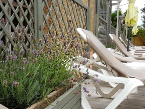 a row of chairs sitting on a porch with flowers at Hotel Castell Blanc in Empuriabrava