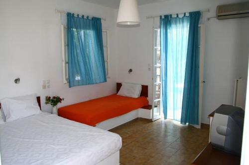 a bedroom with two beds and a tv in it at Hotel Minoa in Katapola