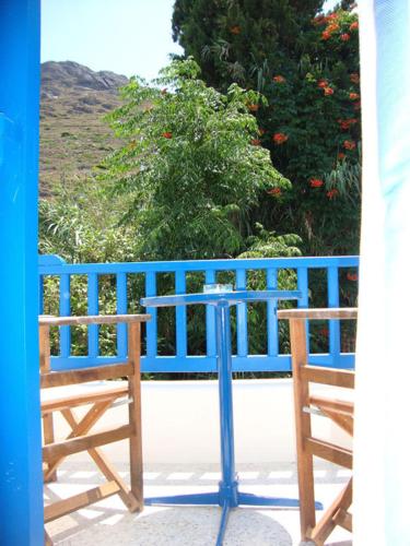 two wooden chairs sitting on a porch with a blue fence at Hotel Minoa in Katapola