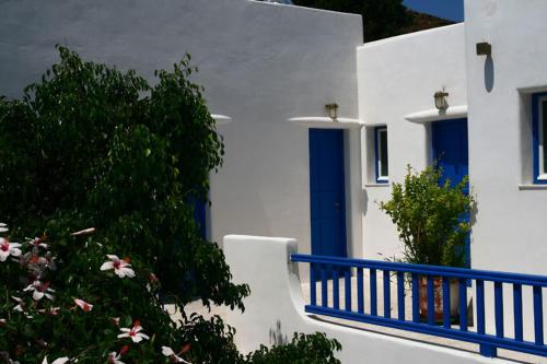 a white building with blue doors and a bush at Hotel Minoa in Katapola