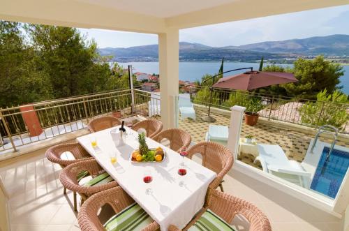 a table and chairs on a balcony with a view of the water at Luxury Villa Star Lights Trogir - heated pool, hot tub, gym, billiard in Trogir