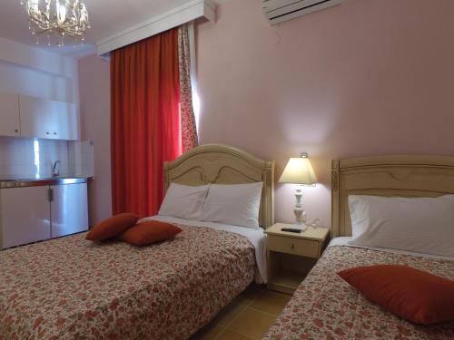 Habitación de hotel con 2 camas y cortina roja en Akrotiri Hotel, en Neos Marmaras