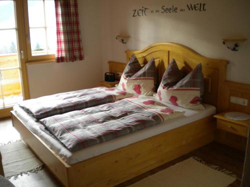 a bedroom with a wooden bed with pillows at Bergpension-Ebental in Brixen im Thale