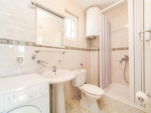 a white bathroom with a toilet and a sink at Apartments NICE in Petrovac na Moru
