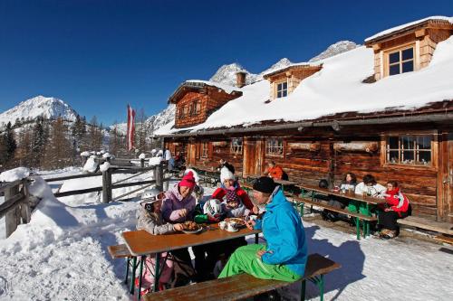 a group of people sitting at a table in front of a cabin at Golf & Skipension Krug in Haus im Ennstal