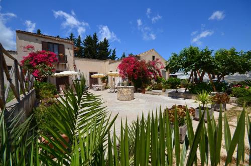 a courtyard of a house with plants and umbrellas at Baglio Ferlito in Buseto Palizzolo