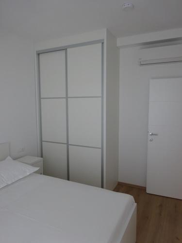 a white bedroom with a bed and a closet at Apartment Duce in Omiš
