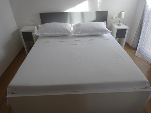 a large white bed with two pillows on it at Apartment Duce in Omiš