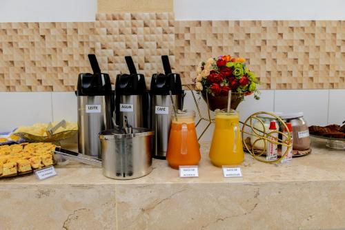 a counter top with bottles and flowers and food at Pojuca Plaza Hotel in Pojuca