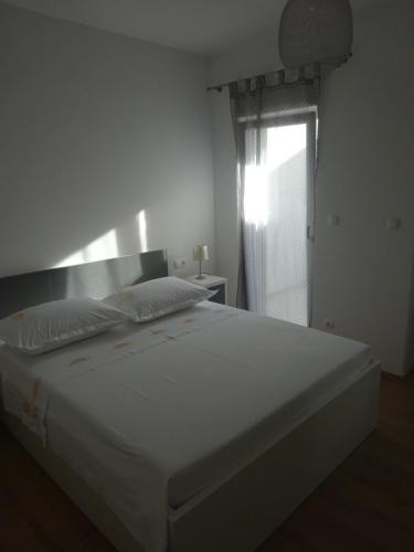 a large white bed in a bedroom with a window at Apartment Duce in Omiš