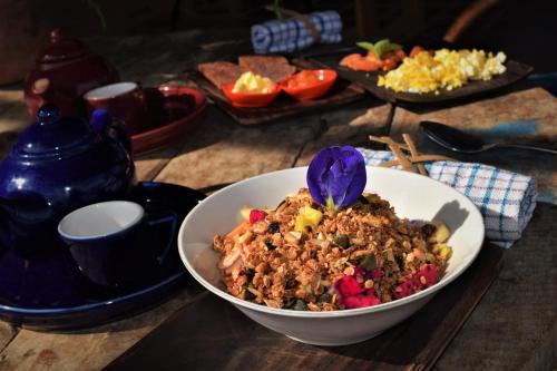 een kom met eten en een paarse bloem op tafel bij Balila Beach Resort in Amed