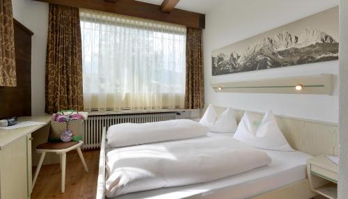 a bedroom with two white beds and a window at Appartements am Römerweg in Oberndorf in Tirol